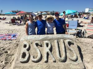 Betsy and her family are shown with their annual sand sculpture in Ocean City, NJ. 2014 featured the family license plate. (From left to right: son Brad, husband Bruce, Betsy, and son Brian)